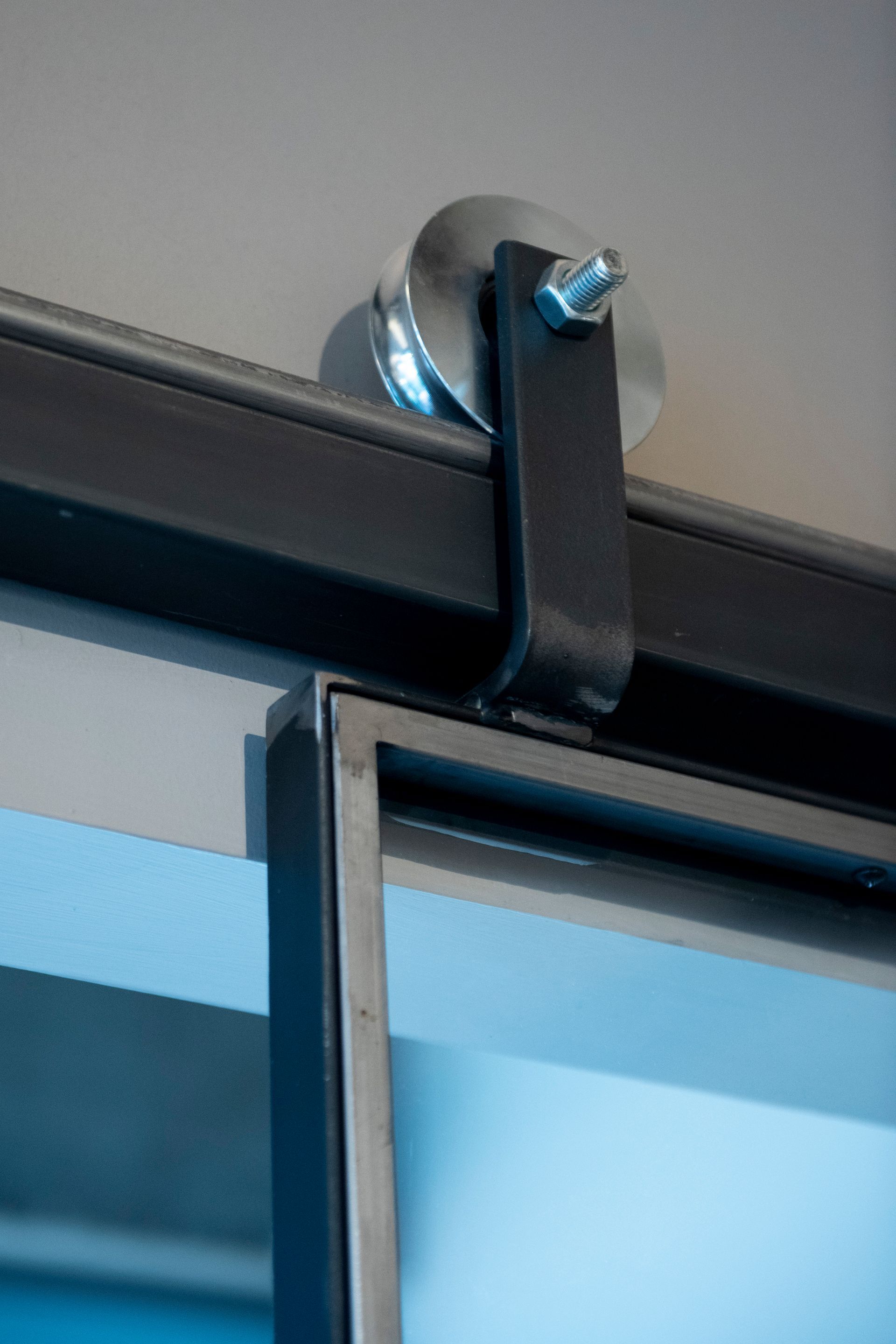 Ferramenta per porte scorrevoli in metallo nero con rullo di grandi dimensioni.