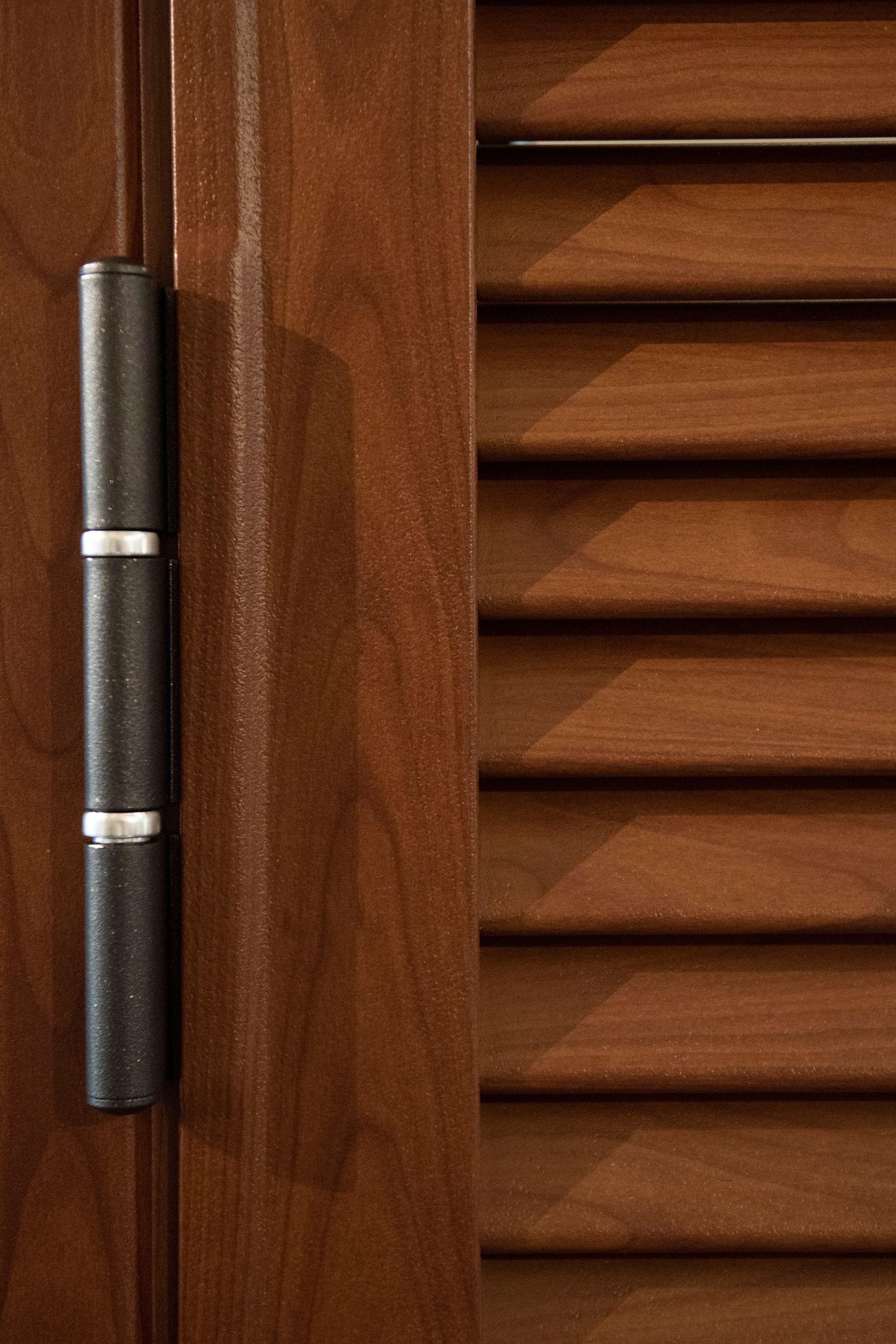 Anta di un mobile in legno marrone scuro con cerniera nera.