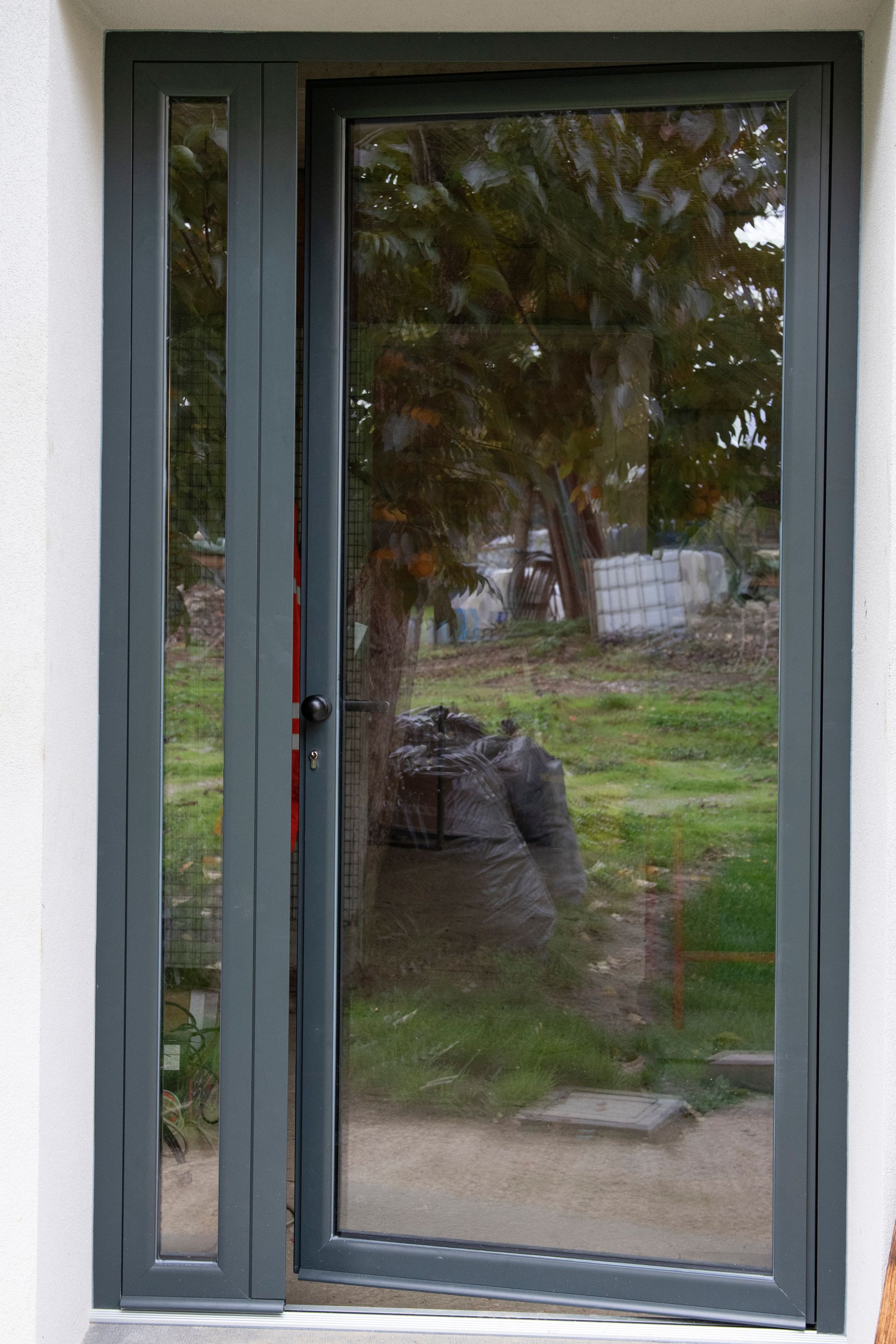 Porta con cornice grigia e luce laterale che riflette la scena esterna.
