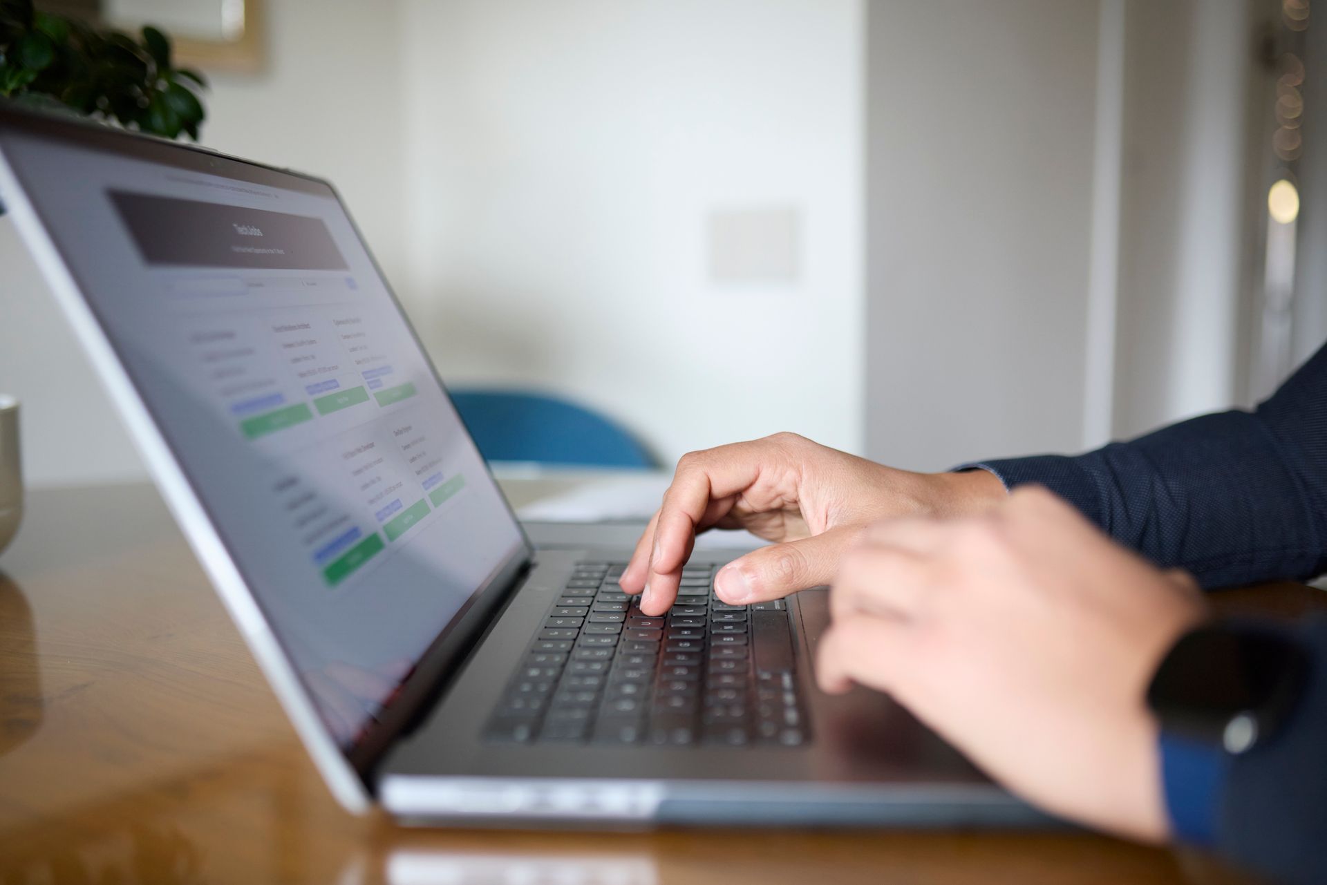 Persona che digita su un computer portatile, con le mani sulla tastiera, in un ambiente interno.