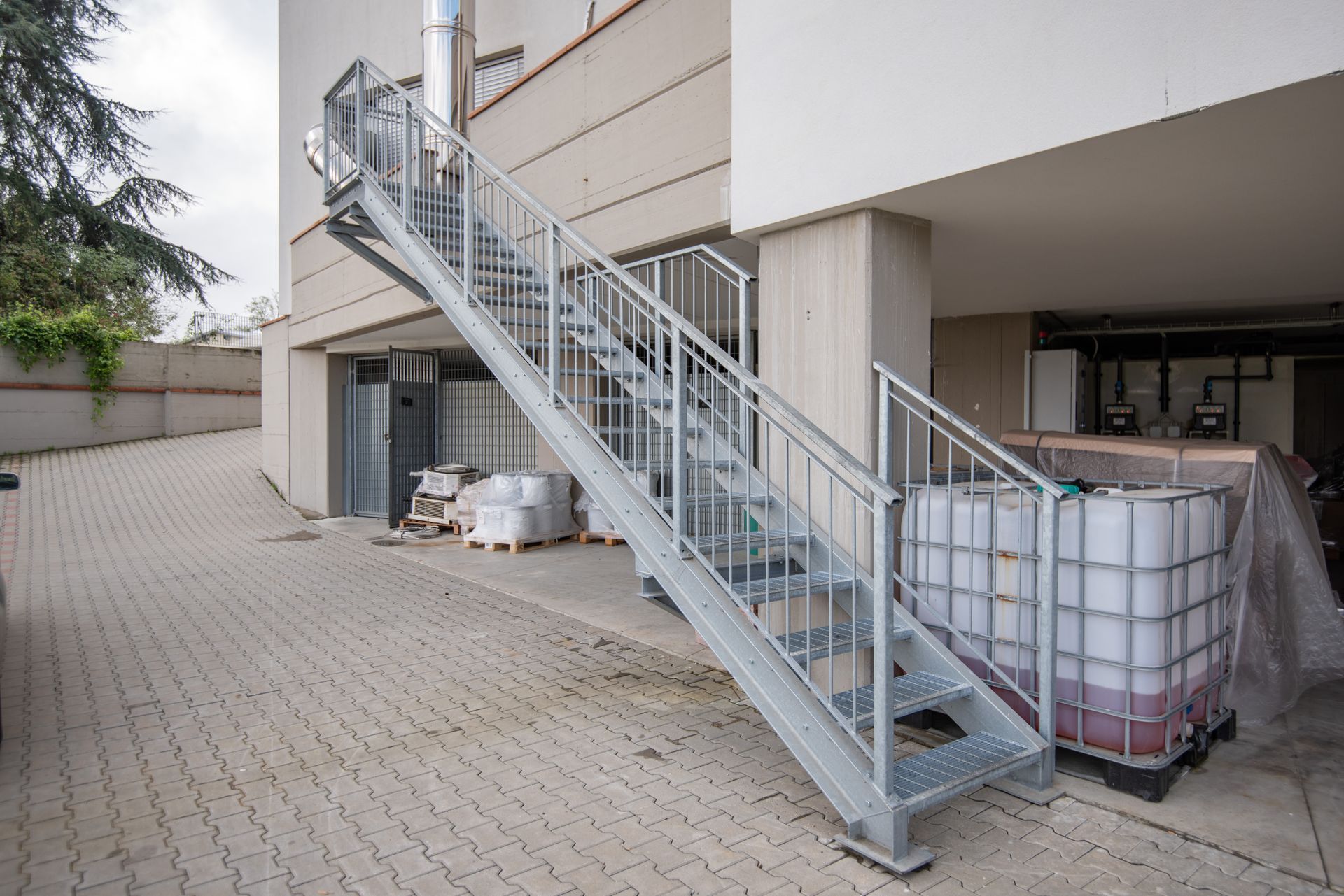 Scala esterna in metallo che conduce alla sommità di un edificio, con corrimano, su una superficie pavimentata.