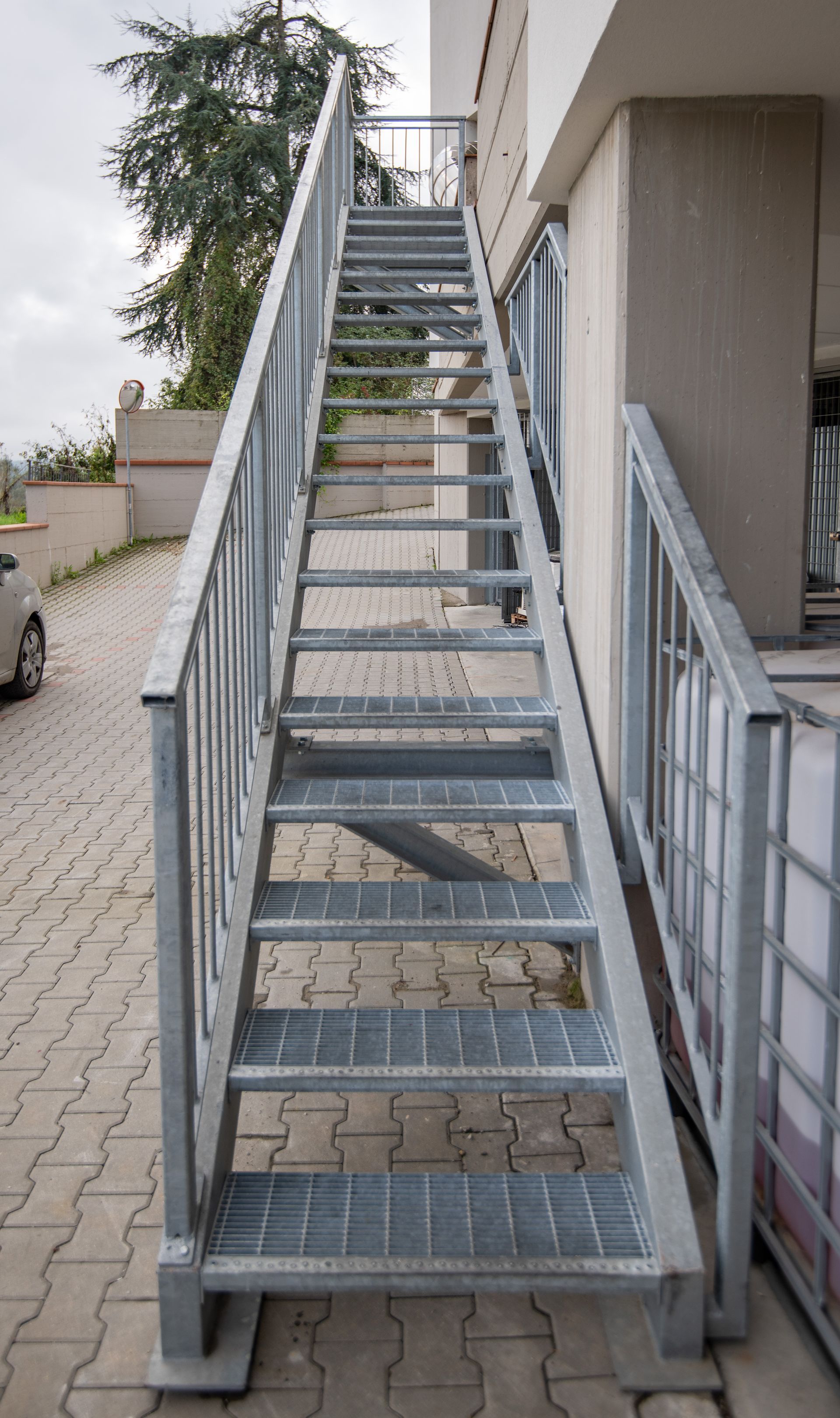 Scala esterna in metallo che conduce alla sommità di un edificio, con corrimano e superficie del gradino a griglia.