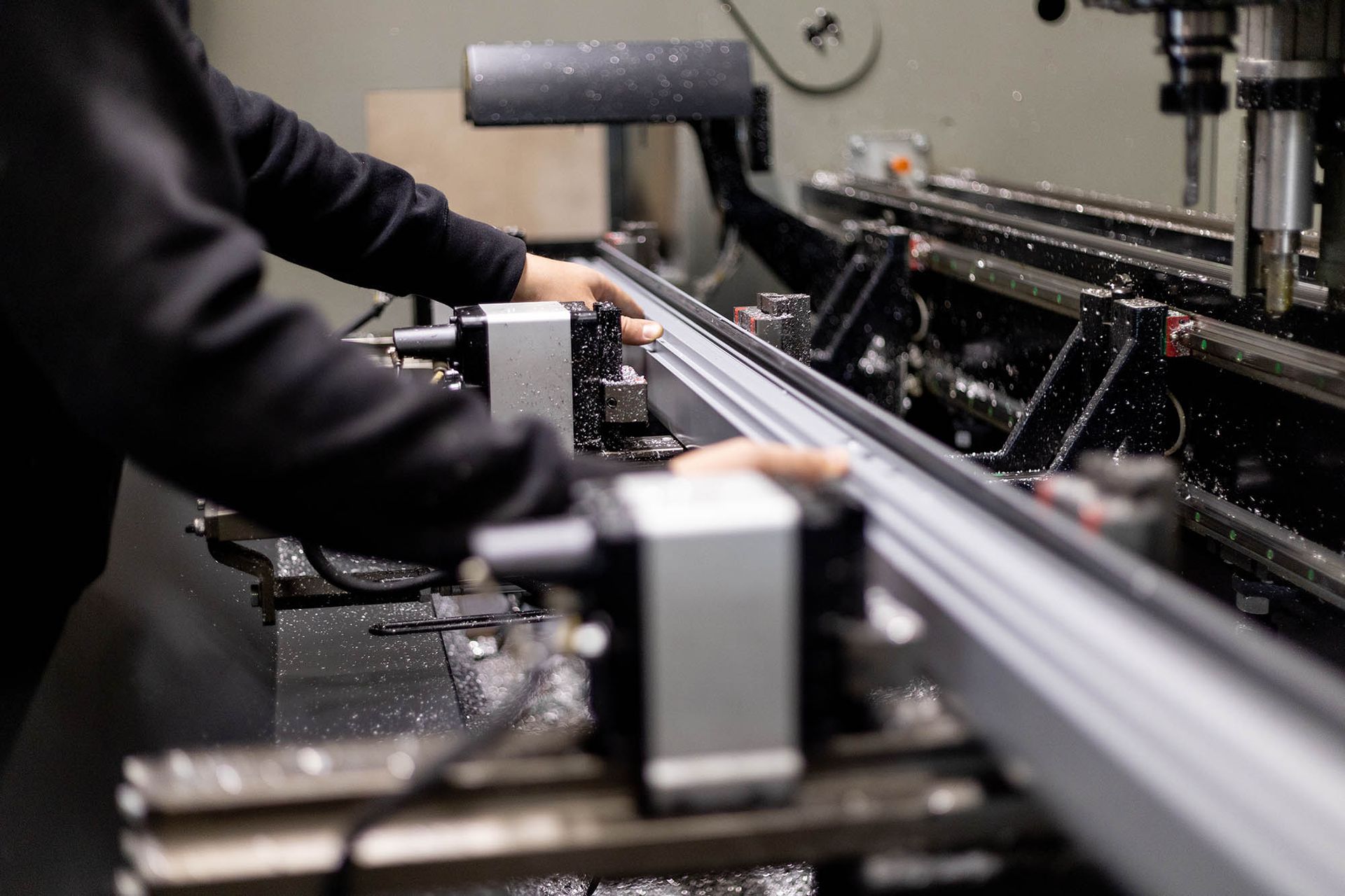 Persona che aziona macchinari e taglia metalli in un'officina.