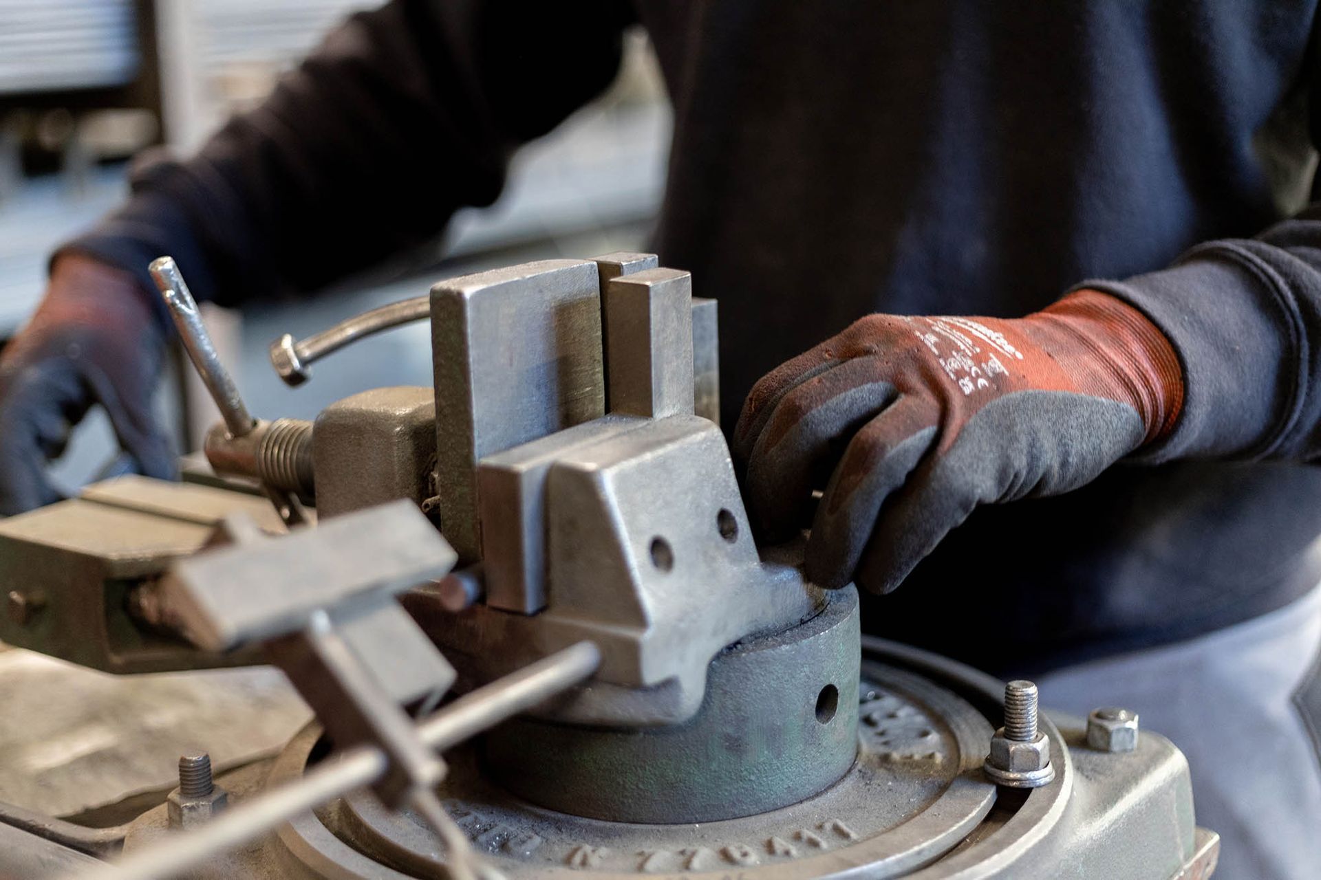 Persona che regola macchinari metallici con le mani guantate.