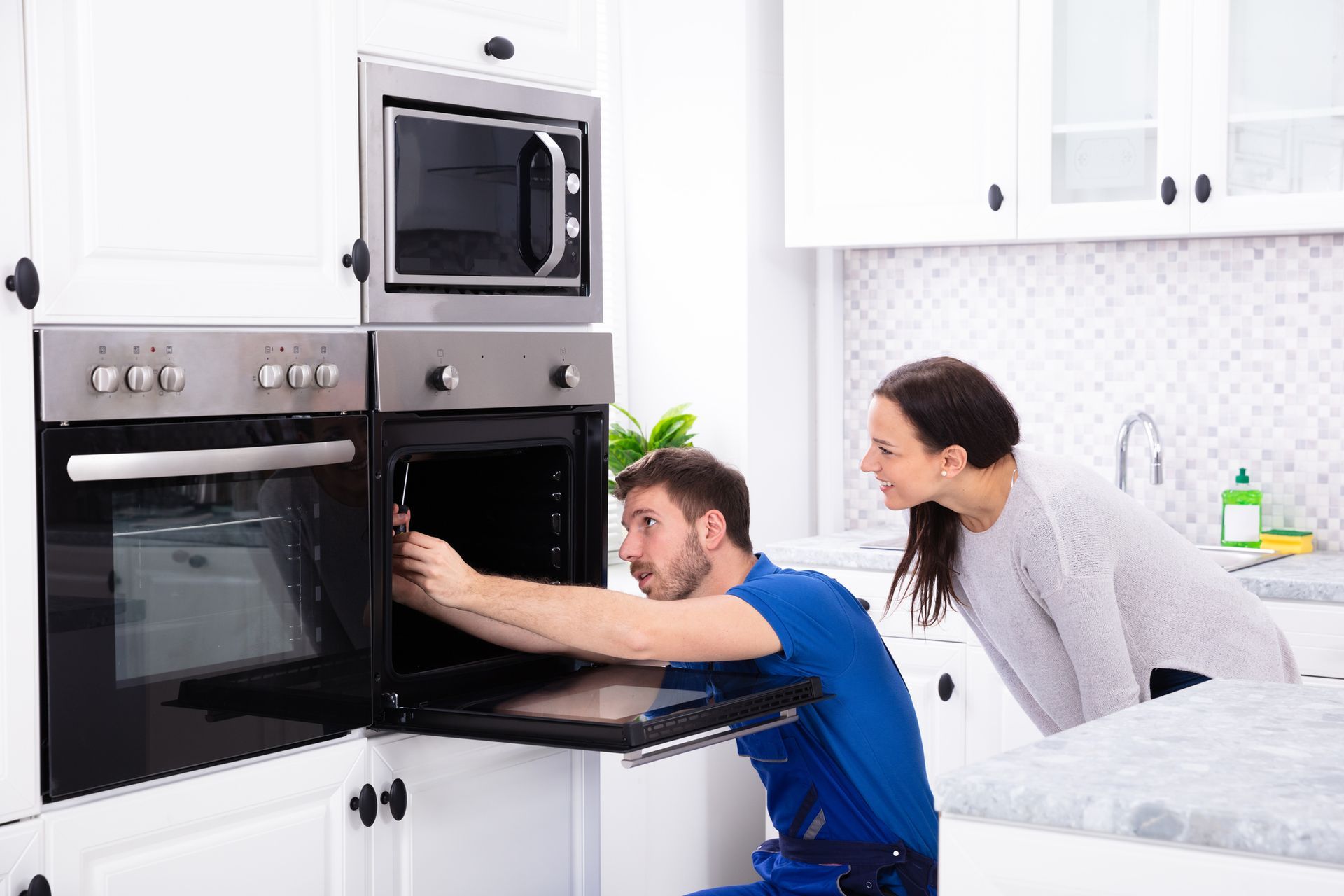 Two men are moving a stove in a kitchen