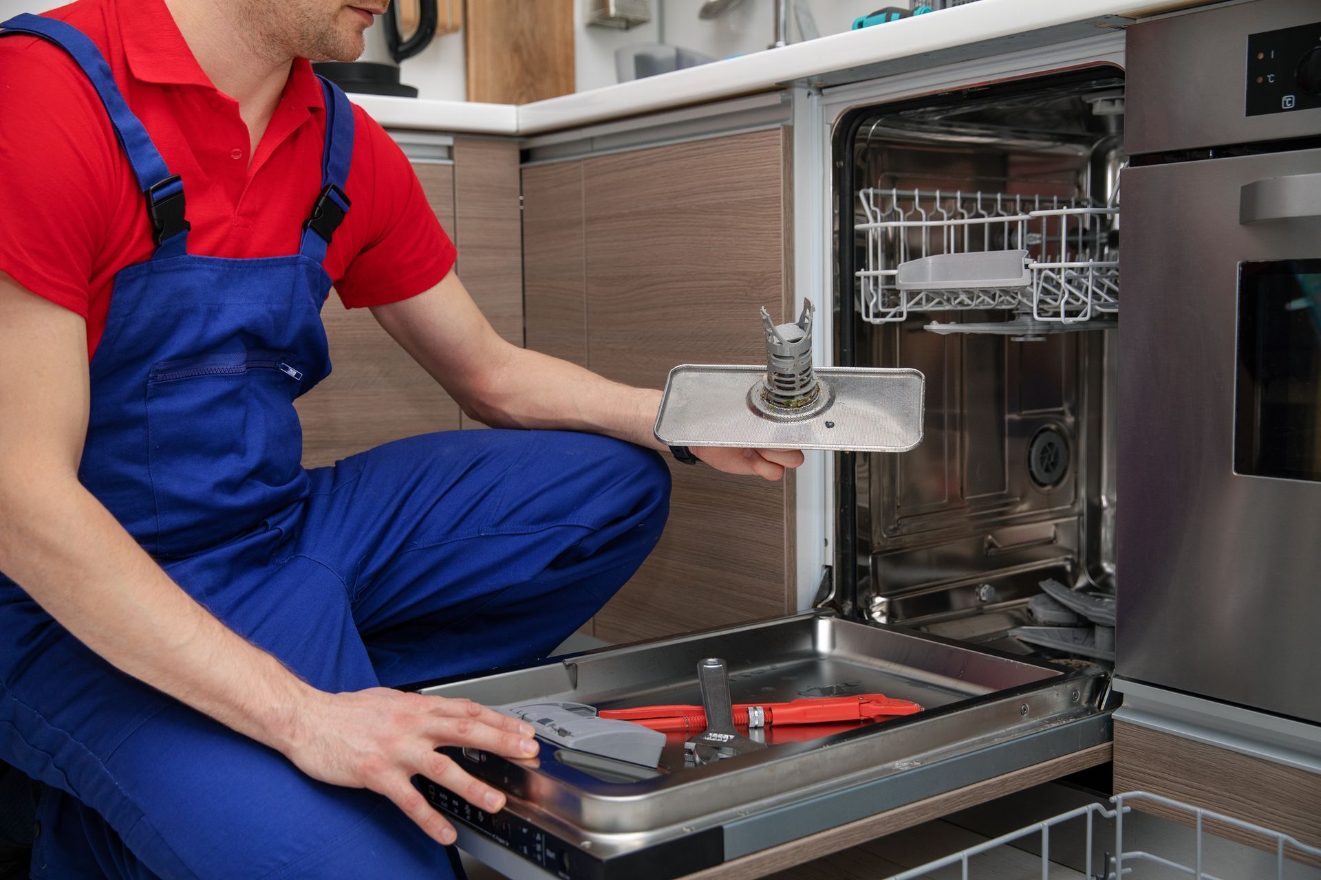 A man is fixing a dishwasher in a kitchen.