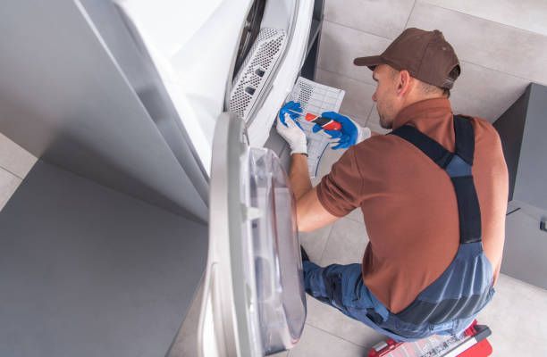 A man is working on a washing machine in a kitchen.