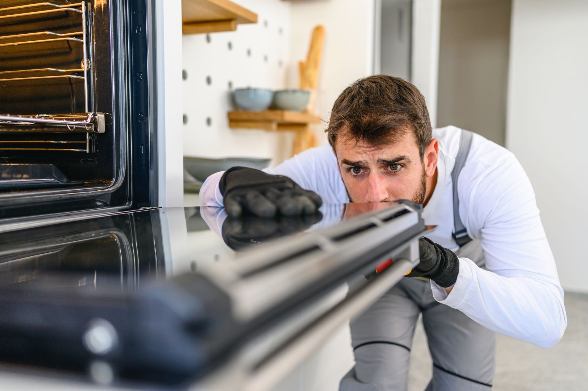A man is cleaning an oven in a kitchen.