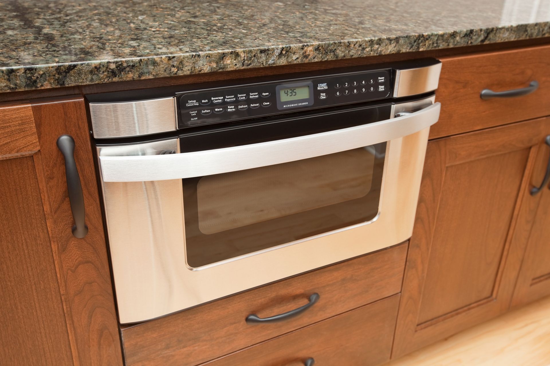 A person wearing green gloves is cleaning a dishwasher with a yellow cloth.