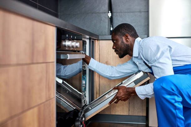 A man is working on an oven in a kitchen.