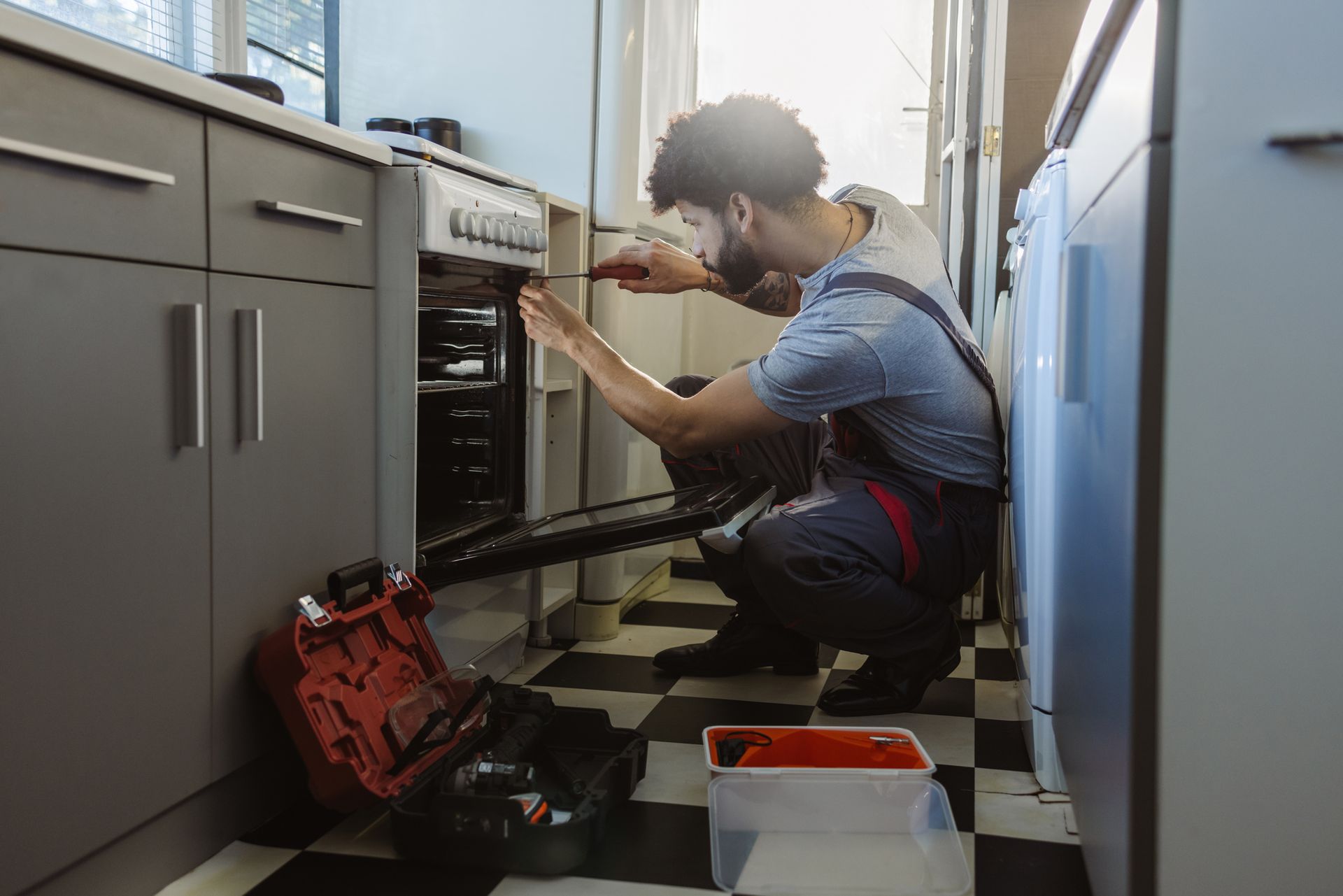 A man is fixing an oven in a kitchen.