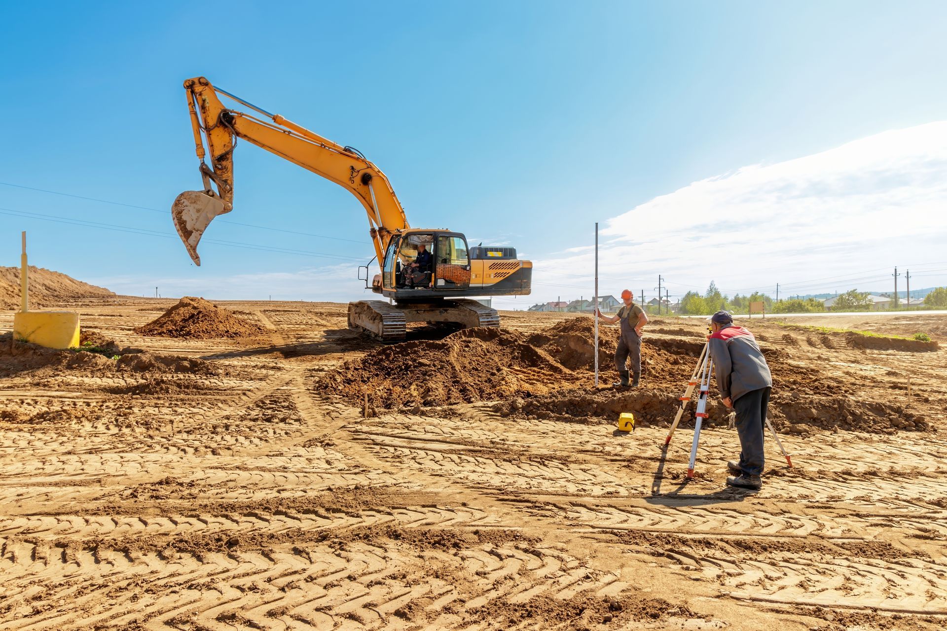 A construction site with a bulldozer and a man standing in the dirt.