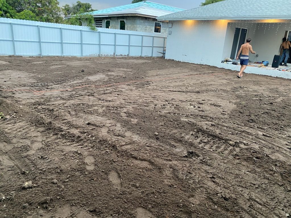 A man is running through a dirt field in front of a house.