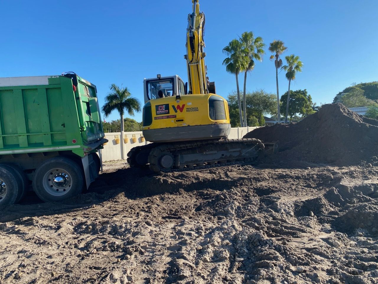 A yellow excavator is loading dirt into a green dump truck.