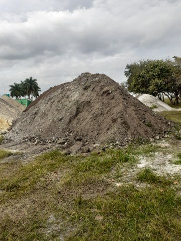 A large pile of dirt is sitting in the middle of a grassy field.
