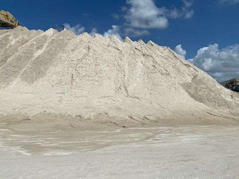 A large pile of sand is sitting on top of a dirt field.
