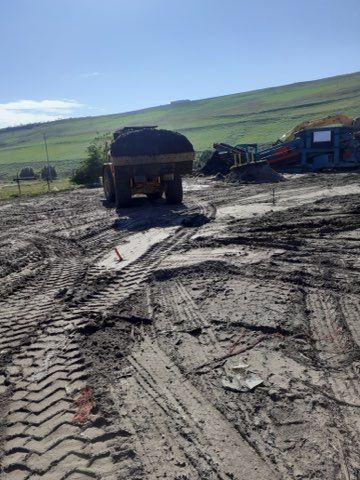 A large dump truck is driving down a muddy road.