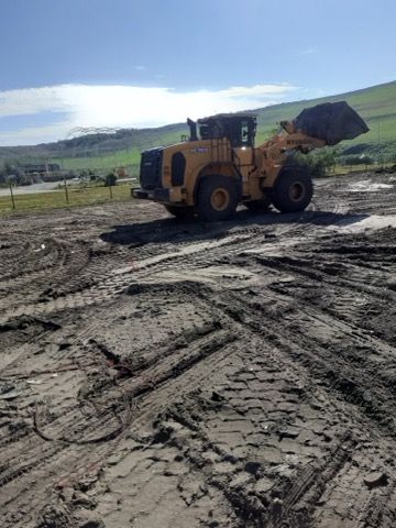 A bulldozer is driving through a muddy field.