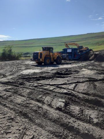 A bulldozer is driving down a dirt road in a field.