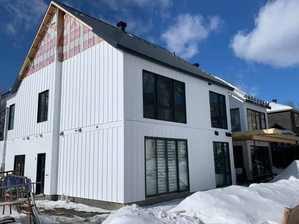Une grande maison blanche est en construction dans la neige.