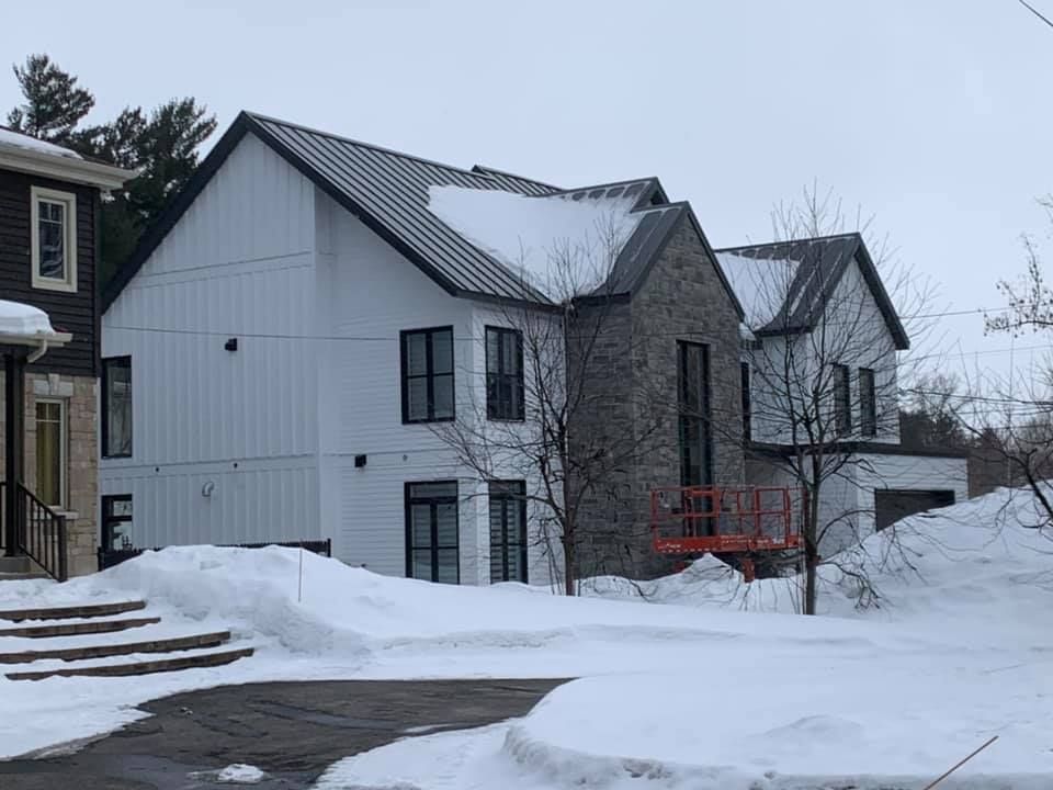 Une rangée de maisons avec de la neige sur le sol devant elles.