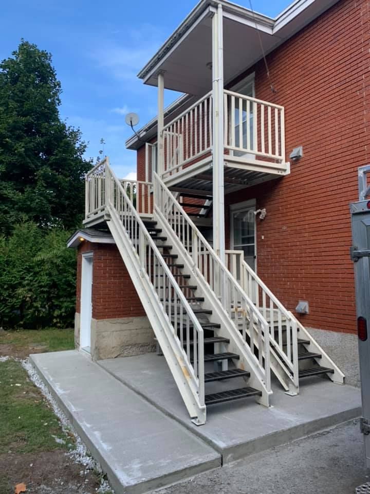 Un ensemble d'escaliers menant à un balcon sur le côté d'un bâtiment en briques.