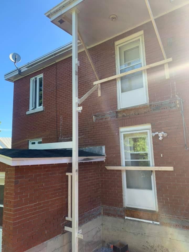 Une maison en briques avec un porche et une antenne parabolique au-dessus.