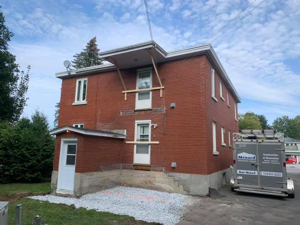 Une maison en briques avec une camionnette garée devant