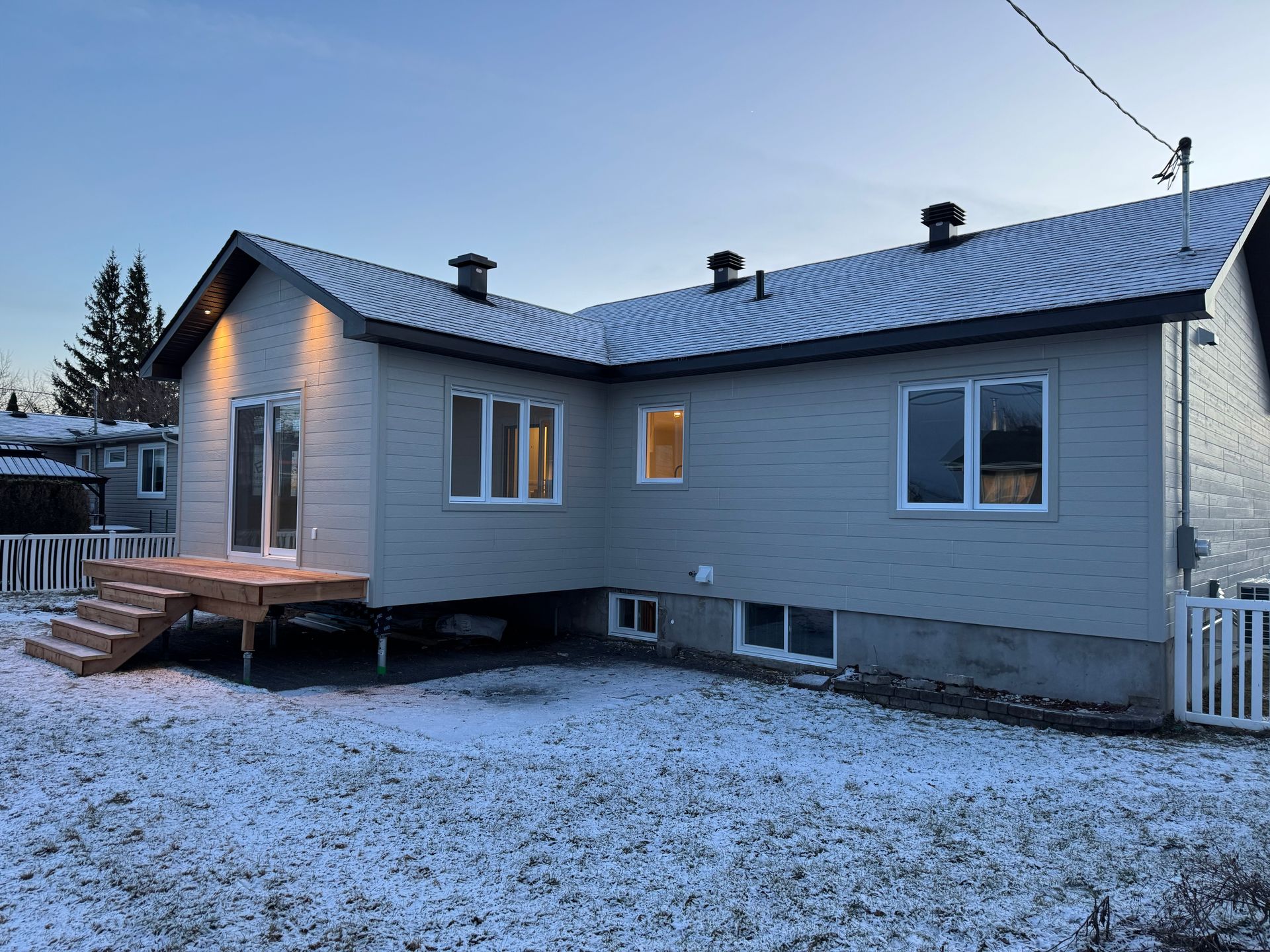 L'arrière d'une maison avec une terrasse et des escaliers dans la neige.