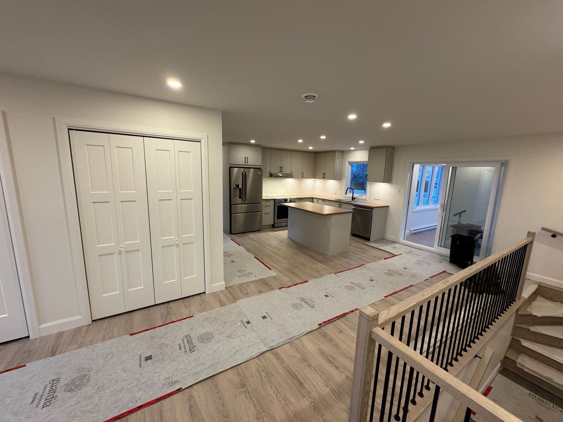 Une cuisine avec un réfrigérateur, un évier et des escaliers.