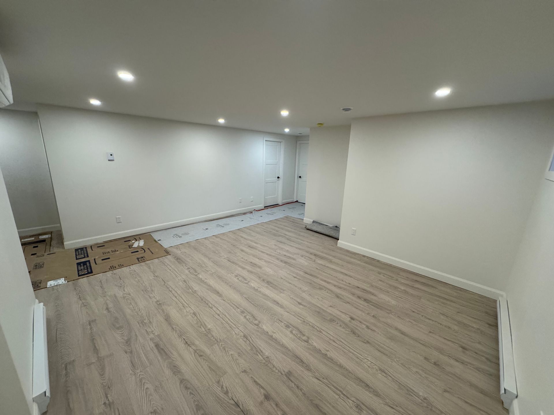 Une grande pièce vide avec du parquet et des murs blancs.