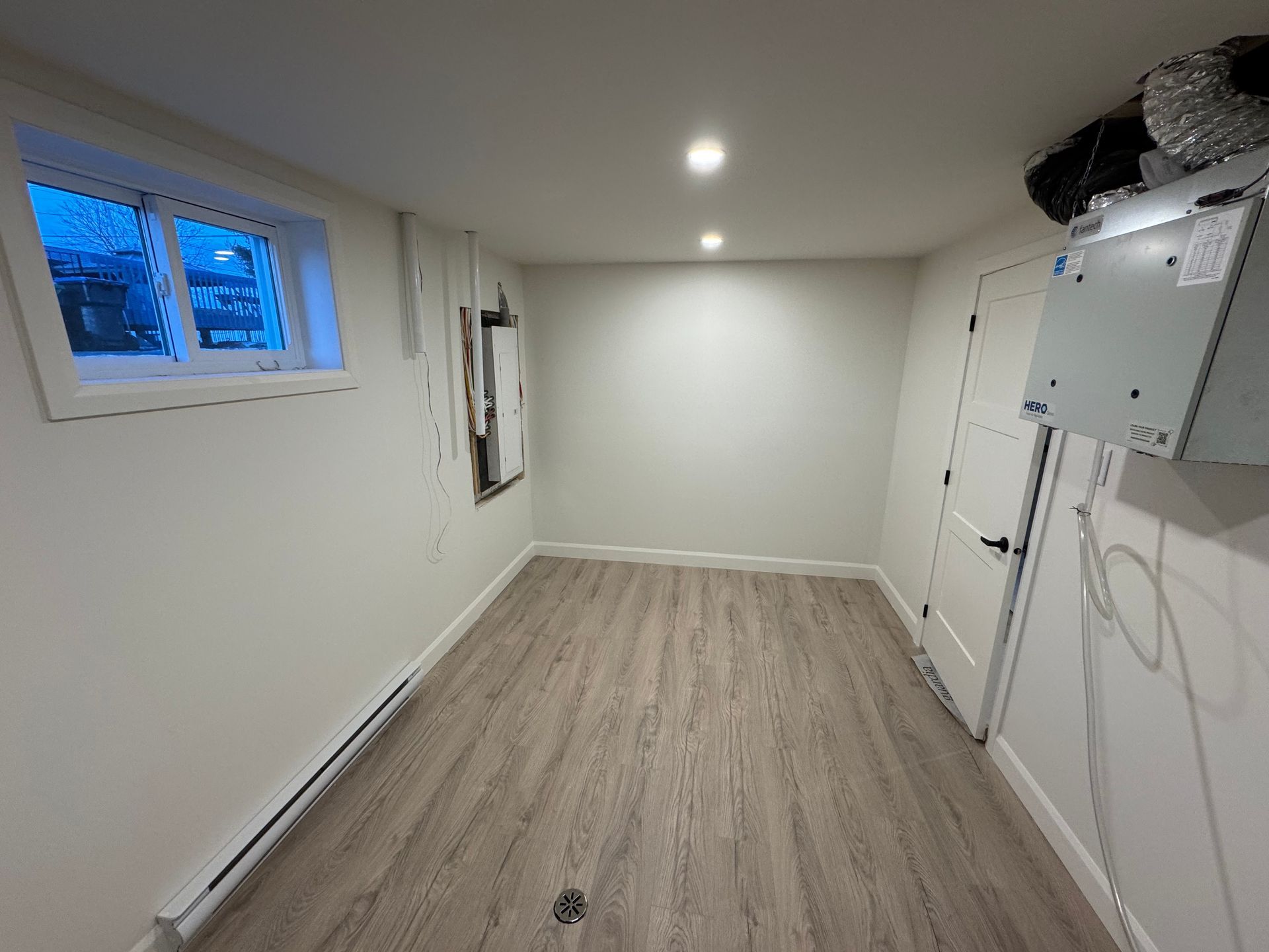 Une pièce vide avec du parquet et des murs blancs.