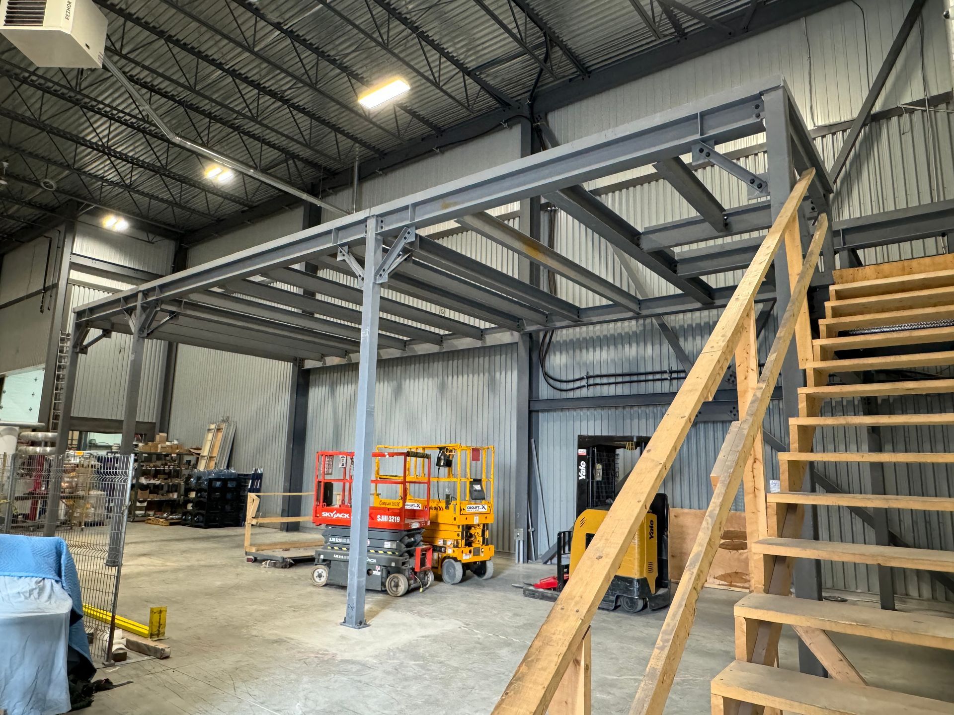 Un grand entrepôt avec des escaliers menant à une mezzanine.