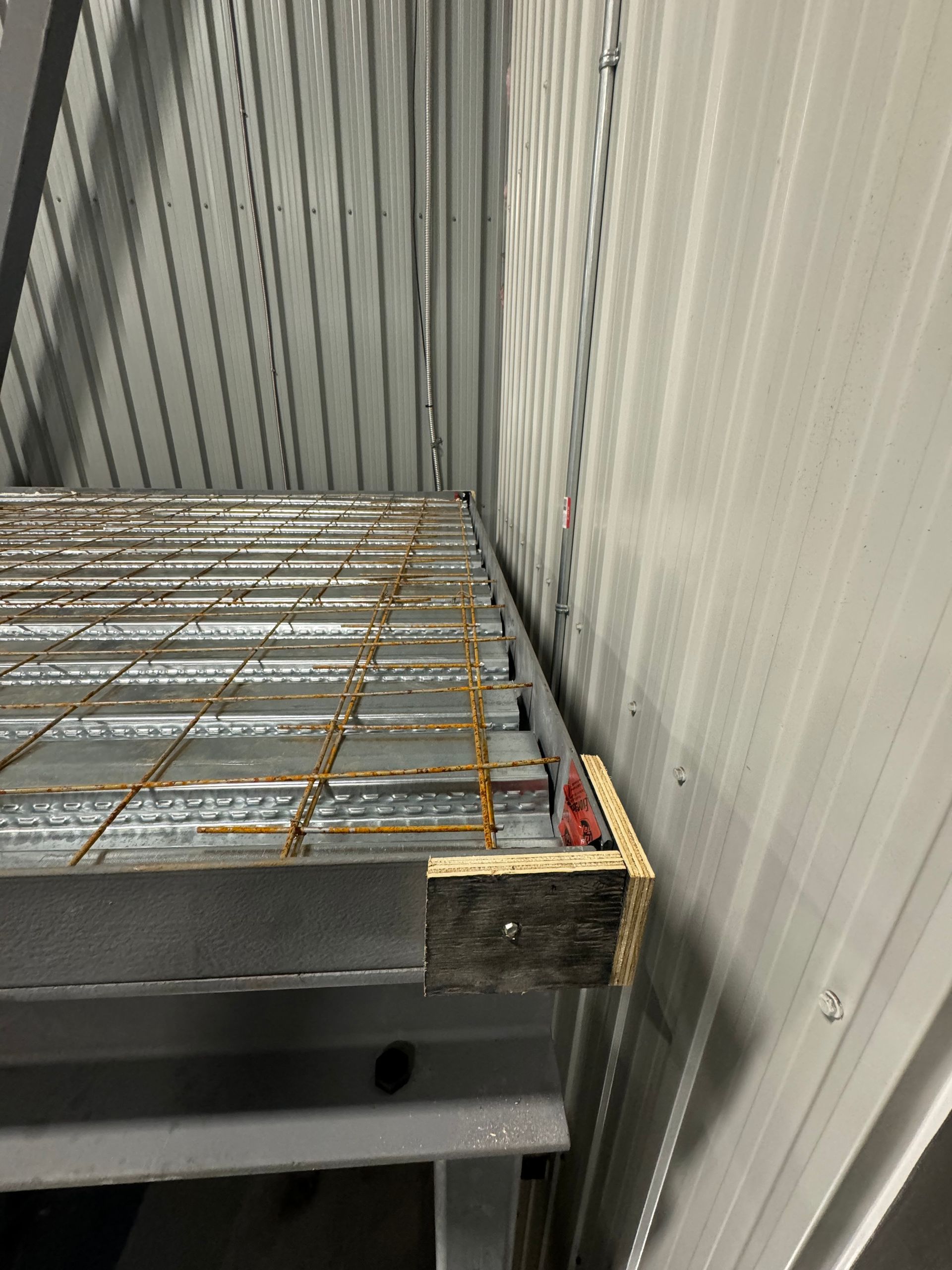 Une étagère en métal est posée dans une pièce à côté d'un mur.