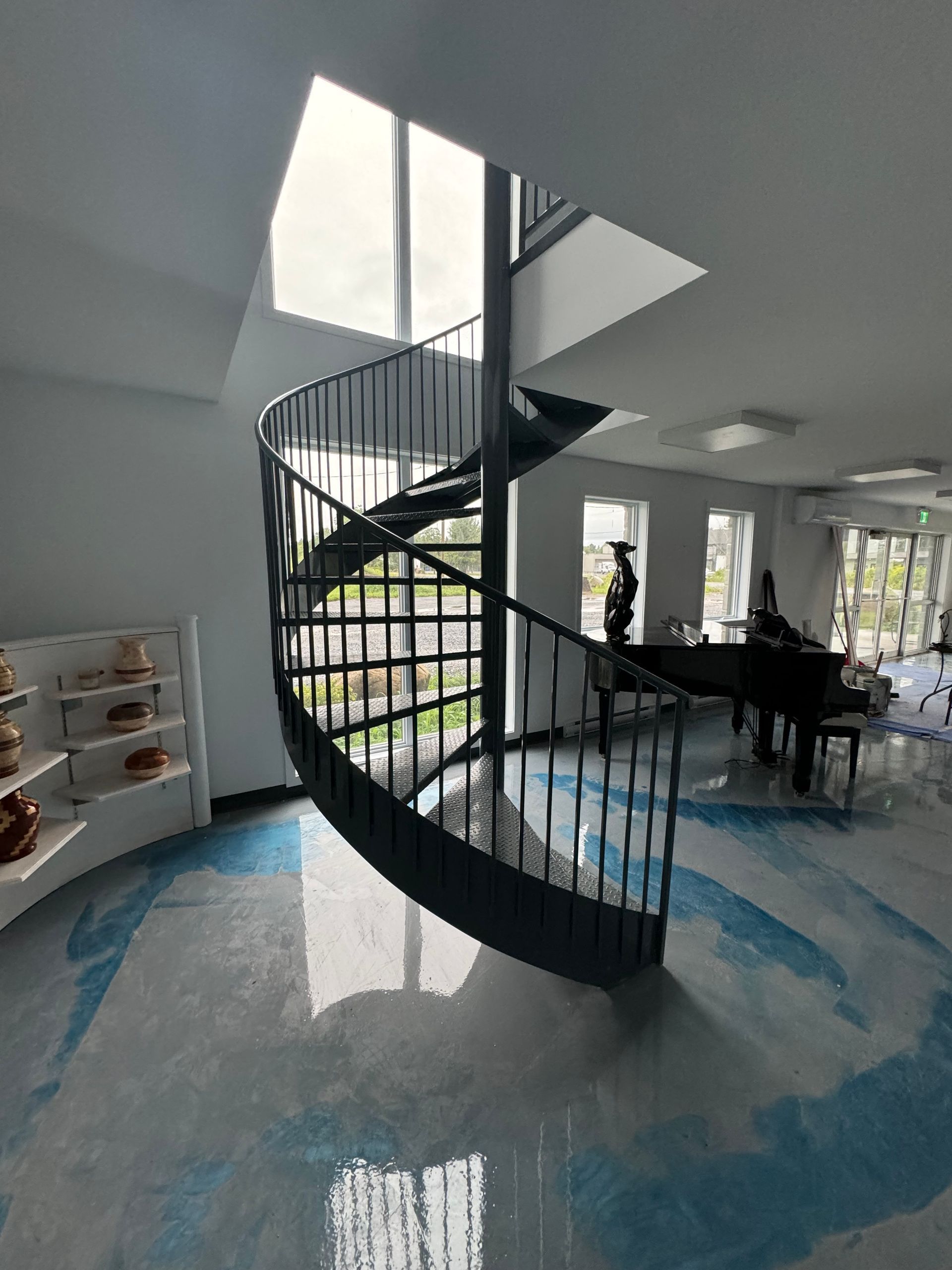 Un escalier en colimaçon dans un salon à côté d'un piano.