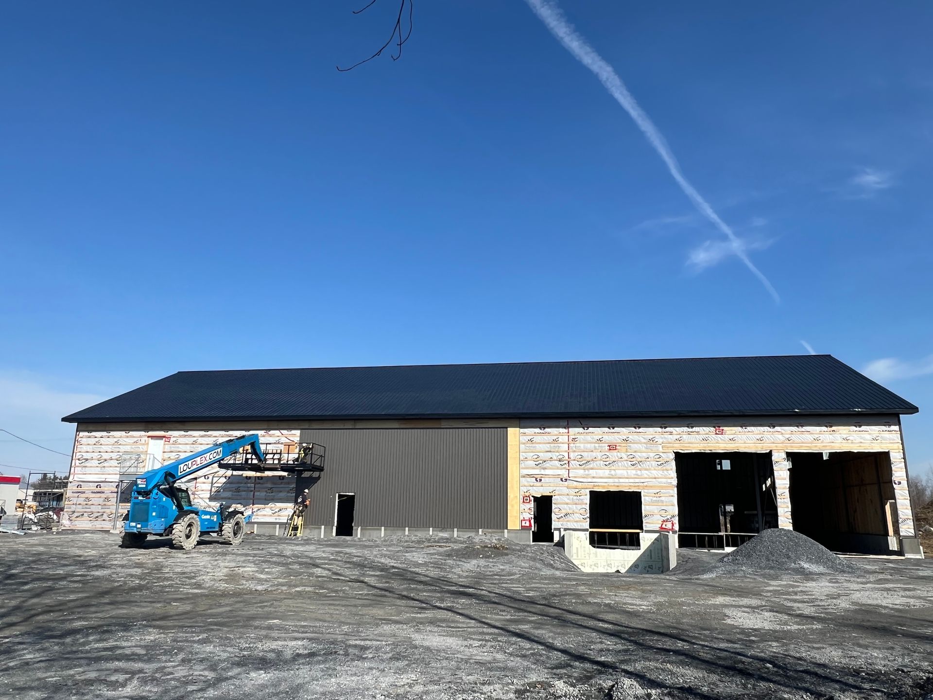 Un grand bâtiment en construction avec une grue bleue devant.