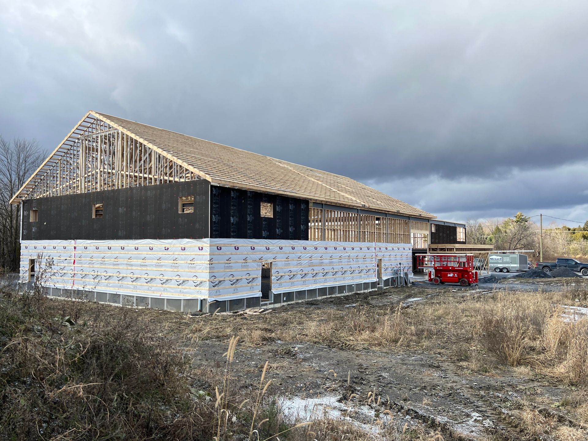 Un grand bâtiment est en construction dans un champ avec un ciel nuageux en arrière-plan.