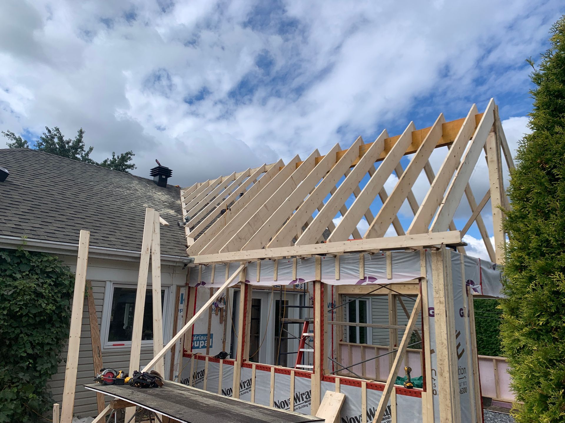 Une maison est en construction avec des poutres en bois et un toit.