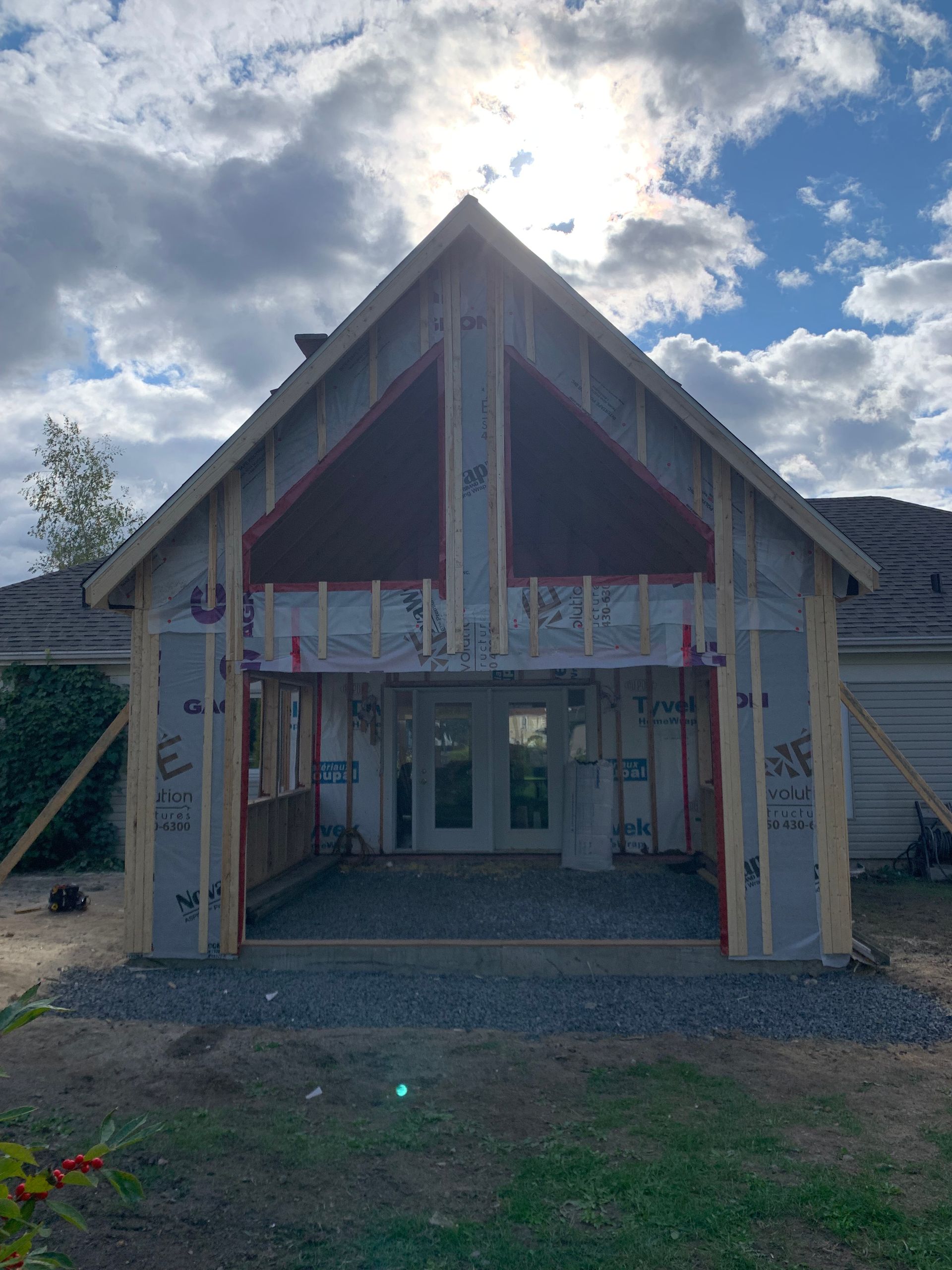 Une maison est en construction avec le soleil qui brille à travers les fenêtres.
