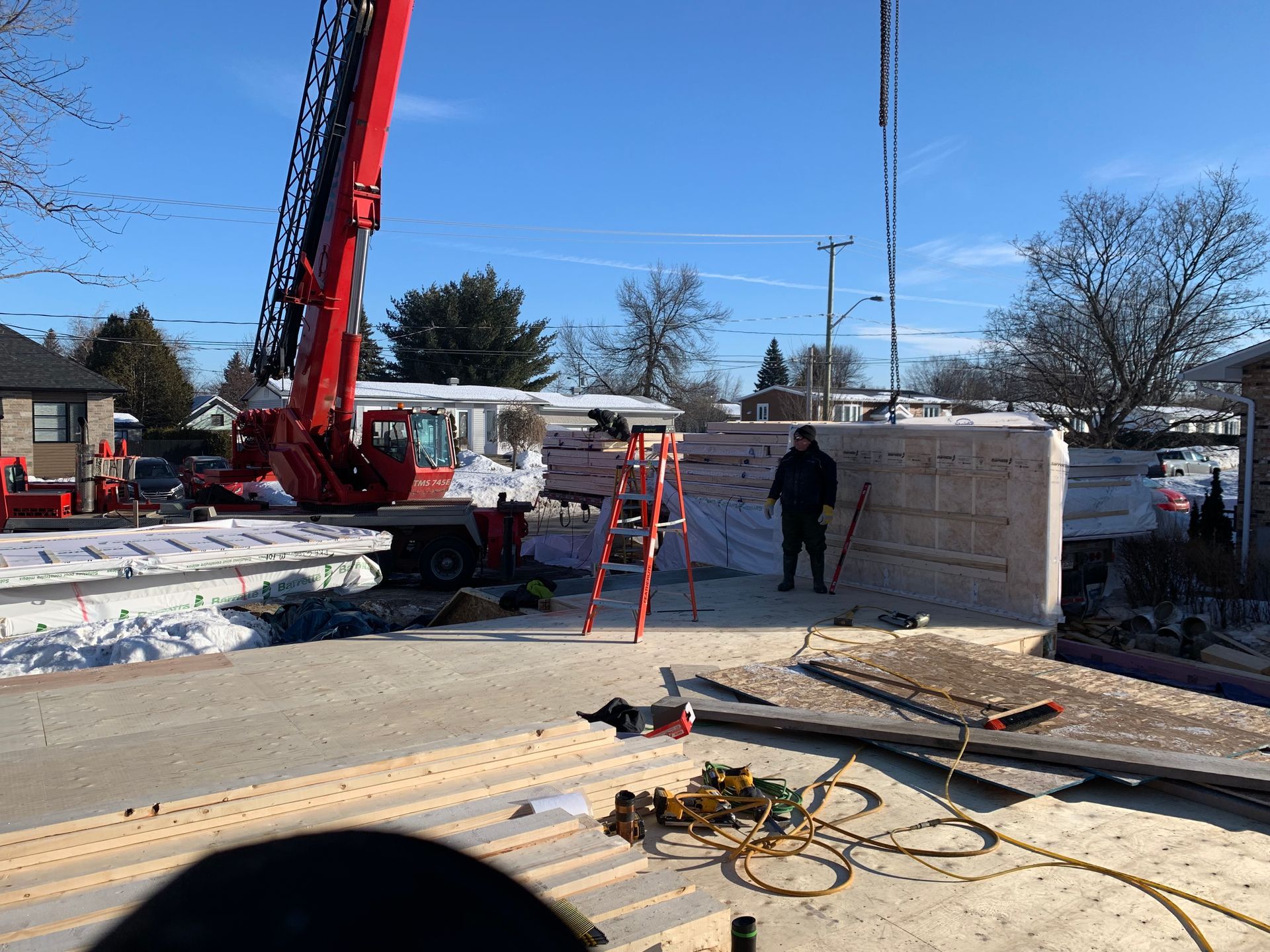 Une grue soulève un mur en béton sur un chantier de construction.