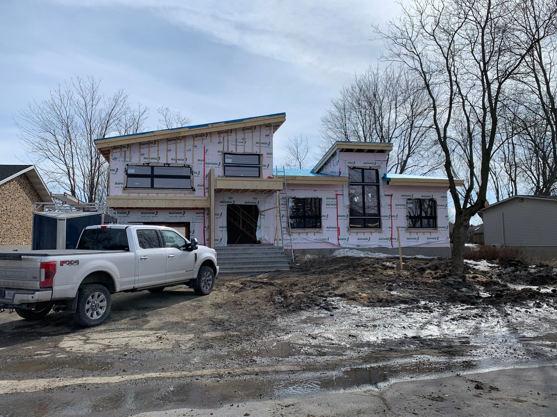 Un camion blanc est garé devant une maison en construction.