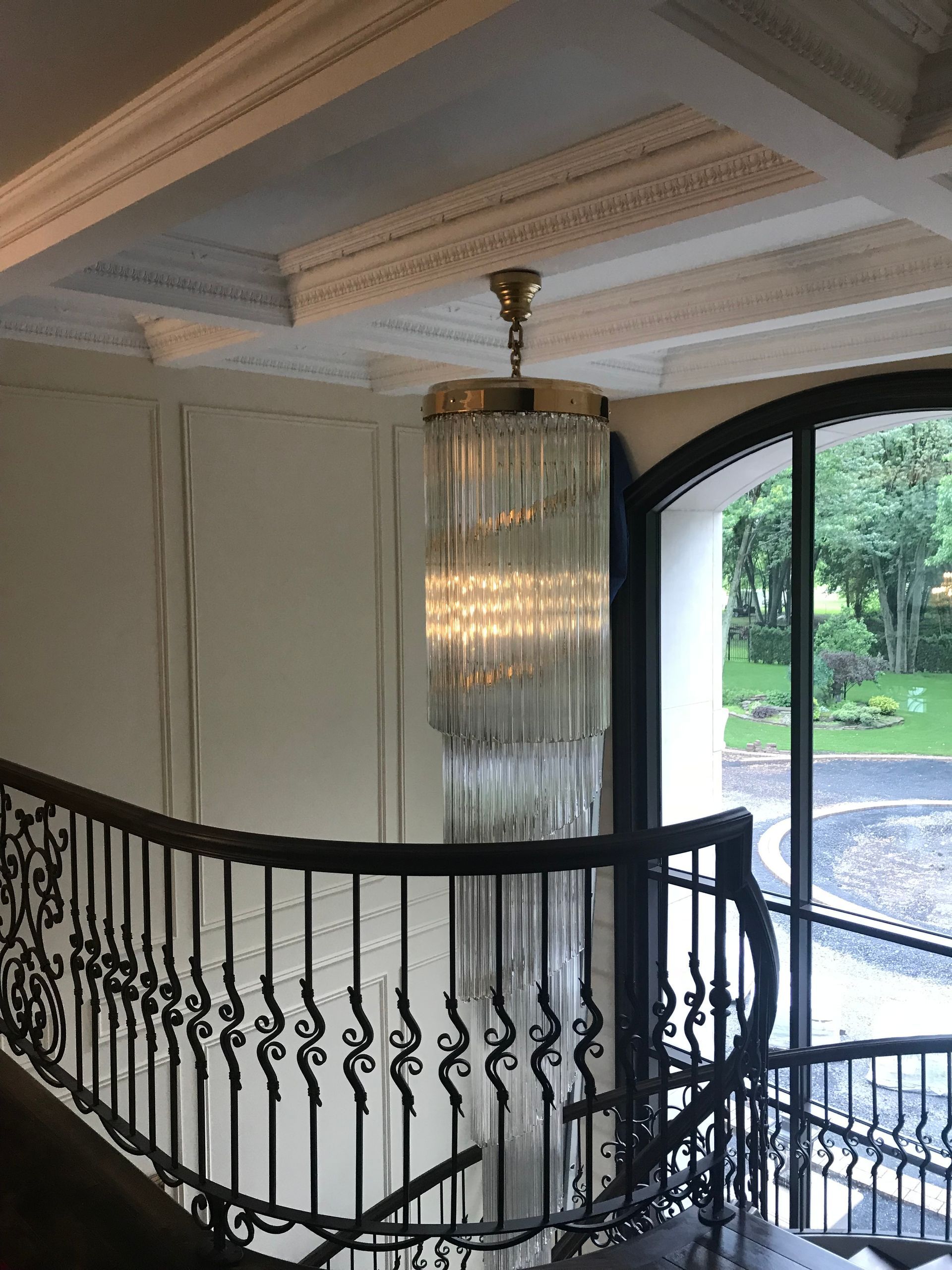 Un escalier avec une rampe en fer forgé et un lustre suspendu au plafond.