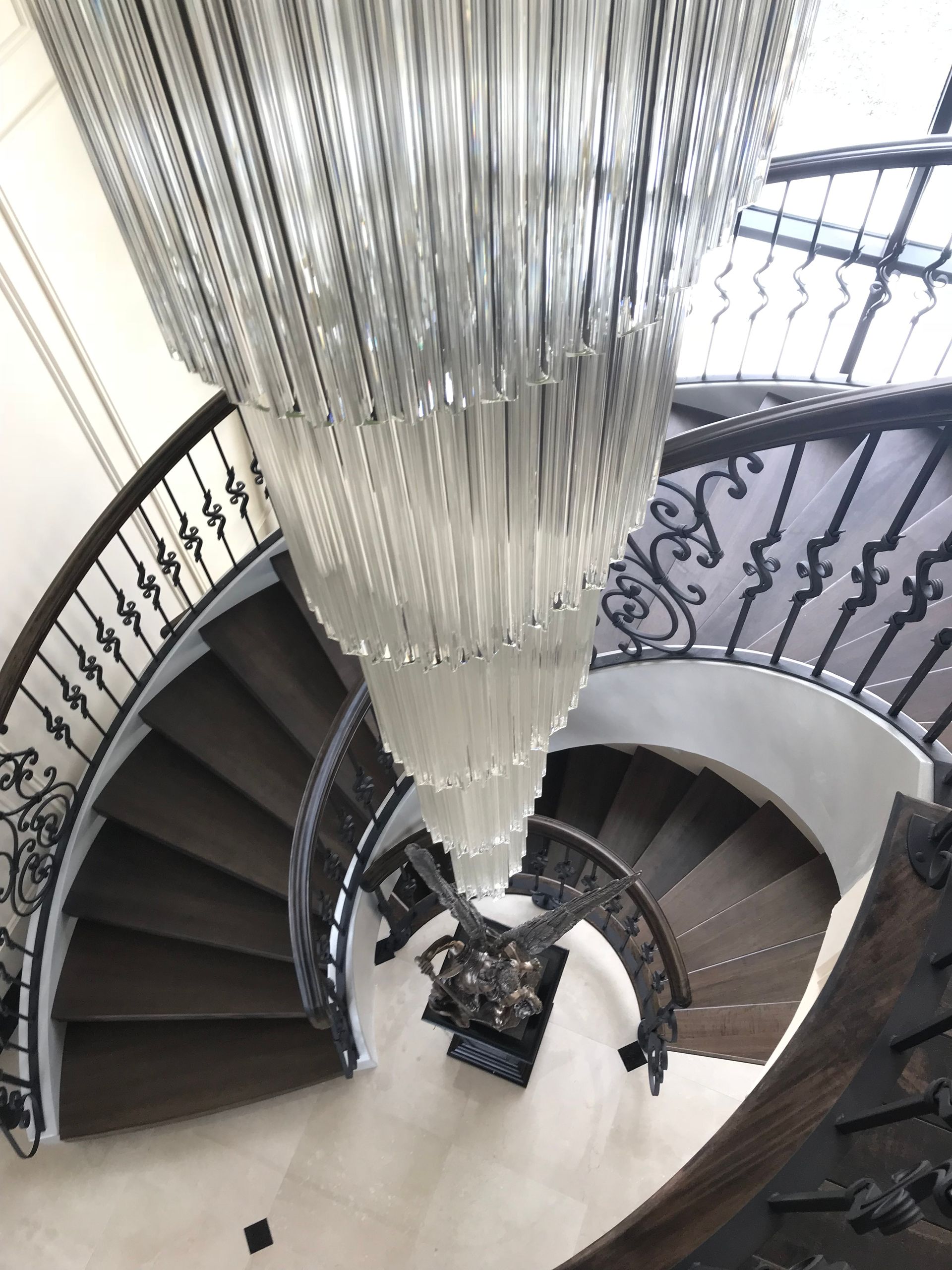 Un escalier en colimaçon avec un grand lustre suspendu au plafond