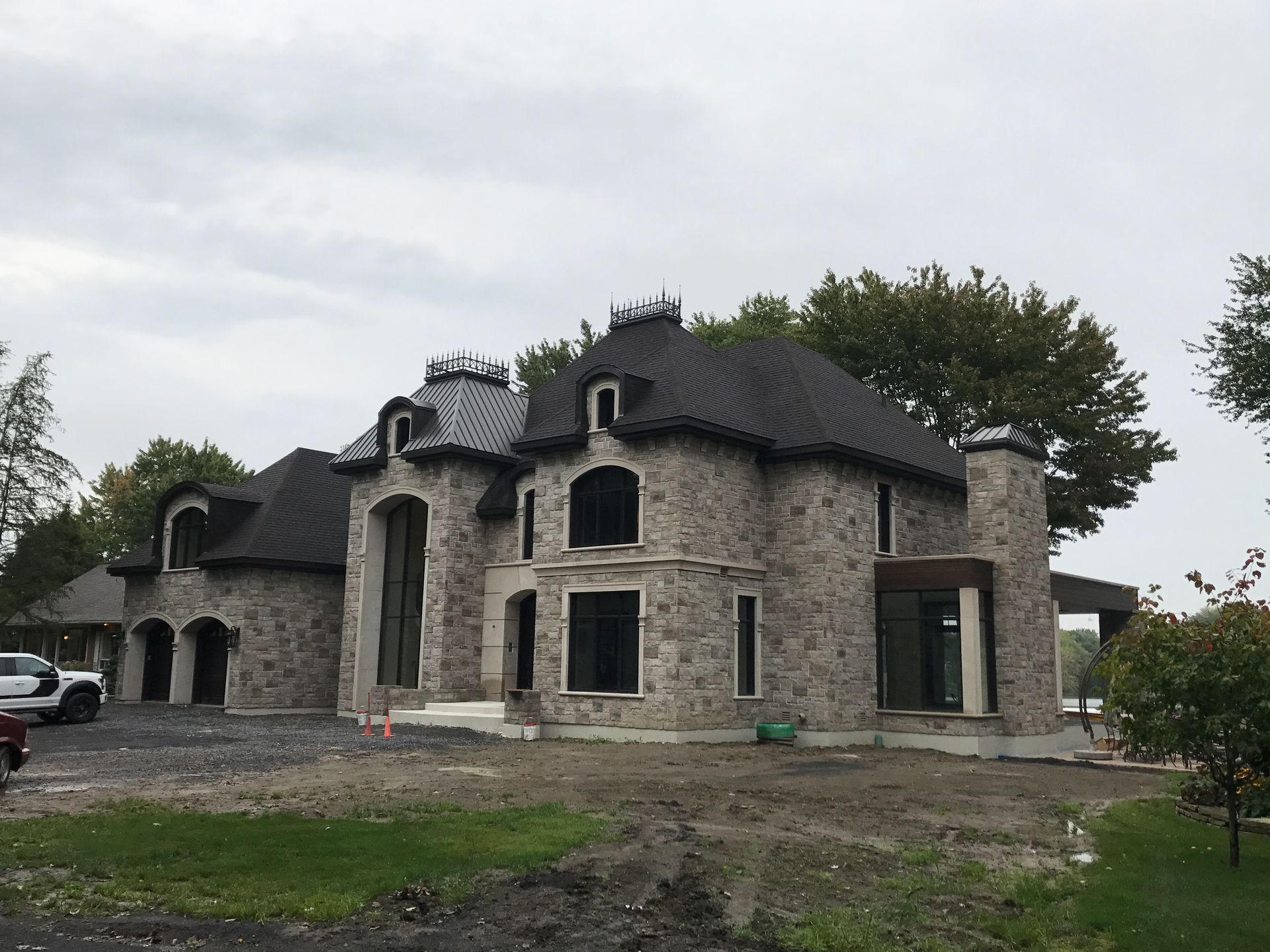 Une grande maison en pierre avec un toit noir est en construction