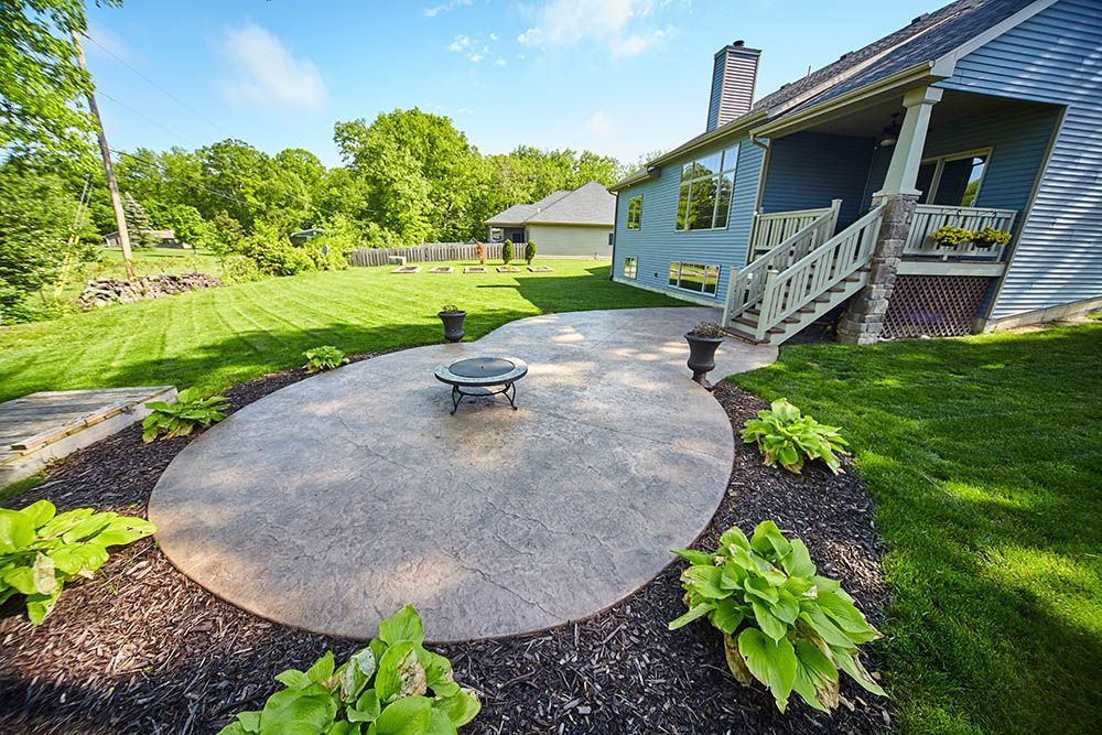 A patio with a fire pit in the middle of it in front of a house.