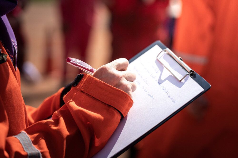 A Person Is Writing On A Clipboard With A Pen — Canary North Pty Ltd In Annandale, QLD