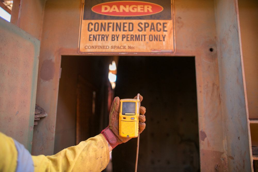 A Person Is Holding A Device In Front Of A Danger Sign — Canary North Pty Ltd In Annandale, QLD