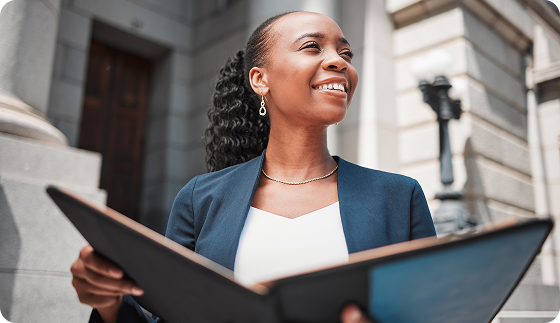 A woman is holding a folder in front of a building.