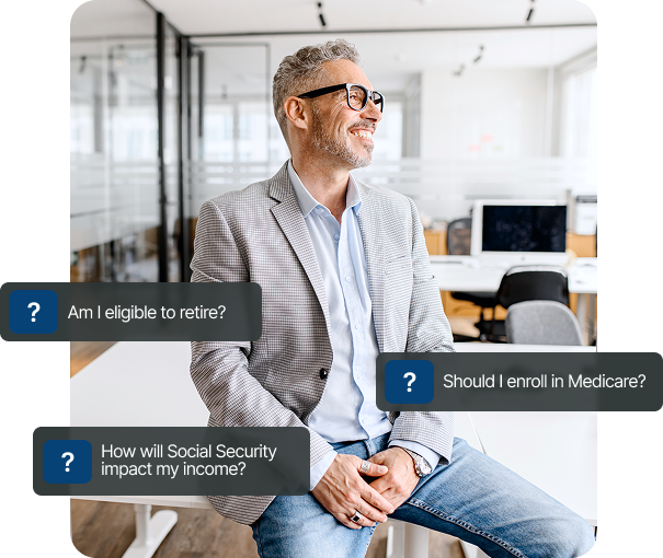 A man in a suit and glasses is sitting on a stool in an office.