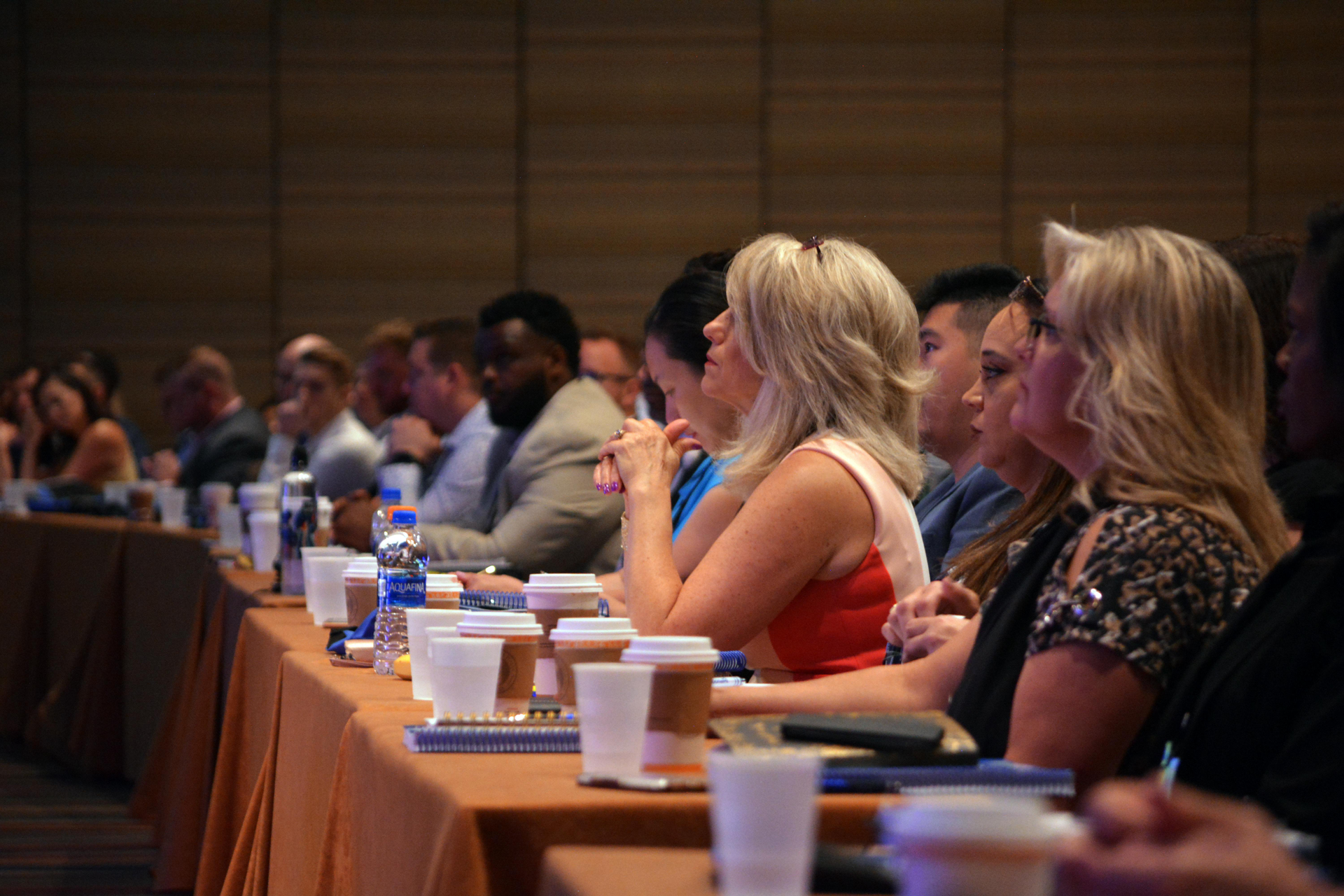 A group of people are sitting at tables in a conference room.